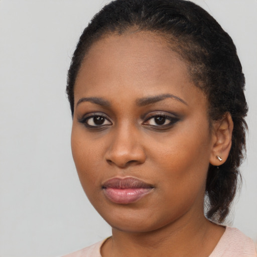 Joyful black young-adult female with long  black hair and brown eyes