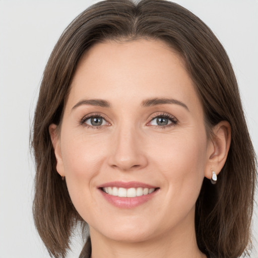 Joyful white young-adult female with medium  brown hair and grey eyes