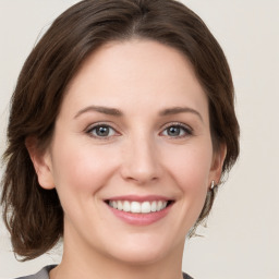 Joyful white young-adult female with medium  brown hair and green eyes