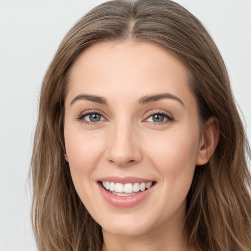 Joyful white young-adult female with long  brown hair and grey eyes