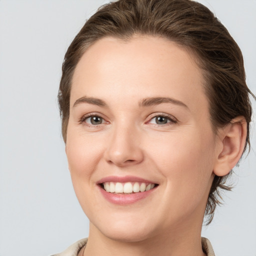 Joyful white young-adult female with medium  brown hair and grey eyes