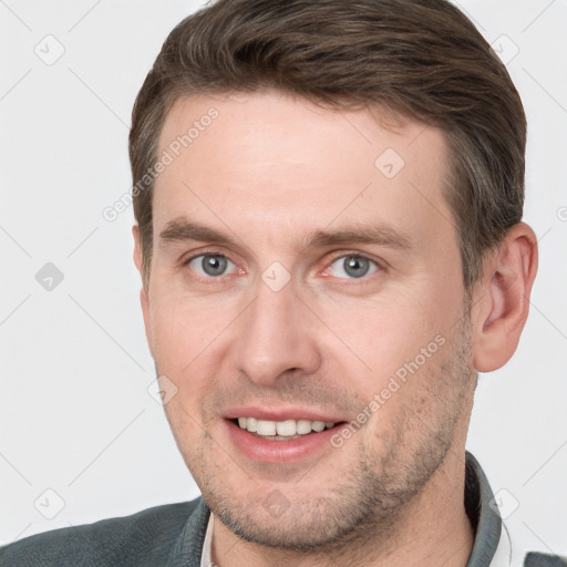 Joyful white young-adult male with short  brown hair and grey eyes