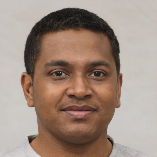 Joyful black young-adult male with short  brown hair and brown eyes