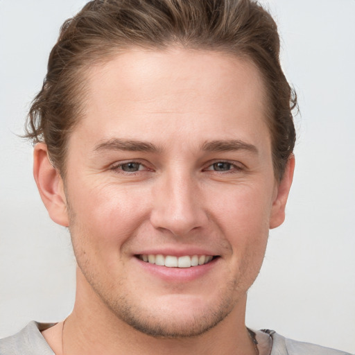 Joyful white young-adult male with short  brown hair and grey eyes