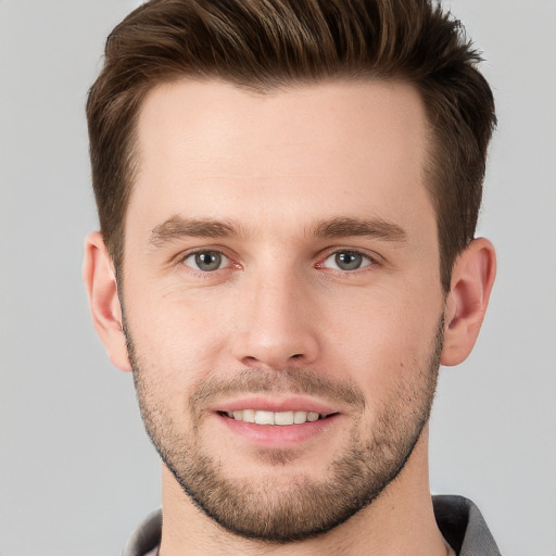 Joyful white young-adult male with short  brown hair and grey eyes