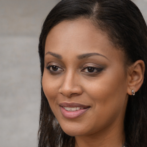 Joyful black young-adult female with long  brown hair and brown eyes