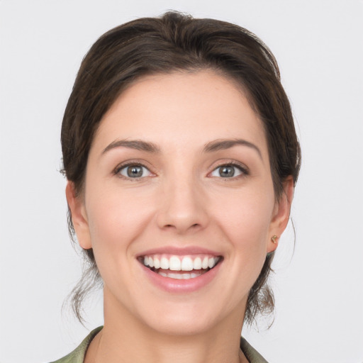 Joyful white young-adult female with medium  brown hair and grey eyes