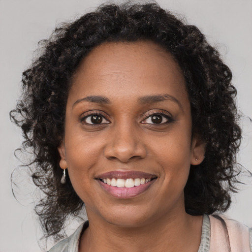 Joyful black young-adult female with long  brown hair and brown eyes