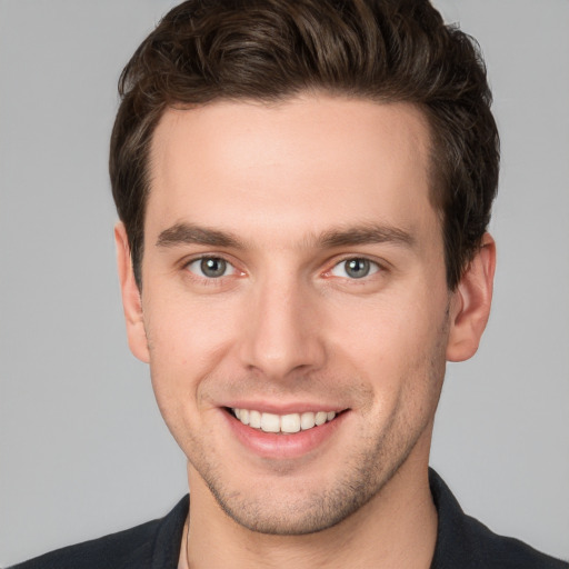 Joyful white young-adult male with short  brown hair and grey eyes