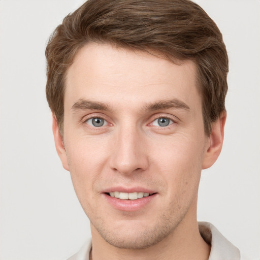 Joyful white young-adult male with short  brown hair and grey eyes