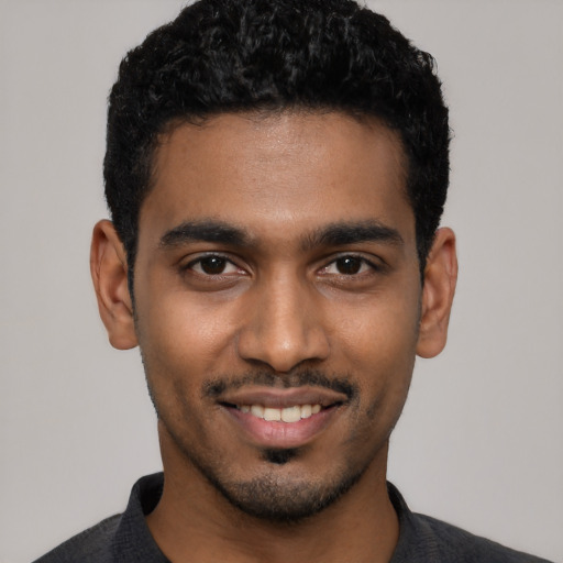 Joyful black young-adult male with short  black hair and brown eyes