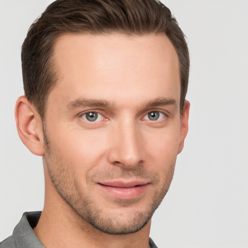 Joyful white young-adult male with short  brown hair and grey eyes