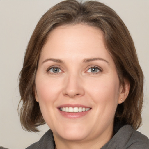 Joyful white adult female with medium  brown hair and grey eyes