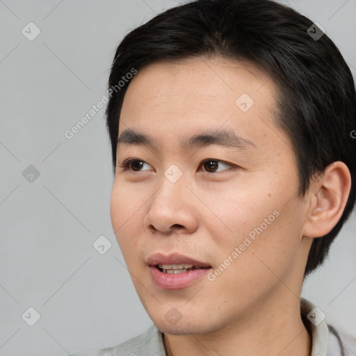 Joyful asian young-adult male with short  brown hair and brown eyes