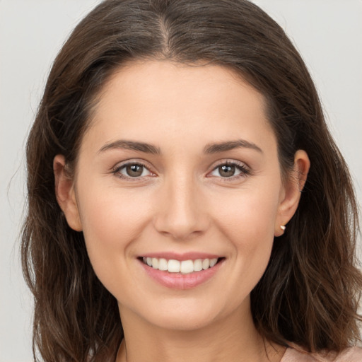 Joyful white young-adult female with long  brown hair and brown eyes