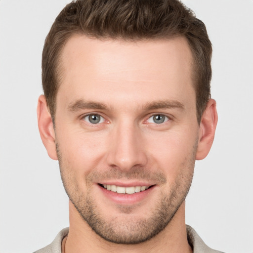 Joyful white young-adult male with short  brown hair and grey eyes