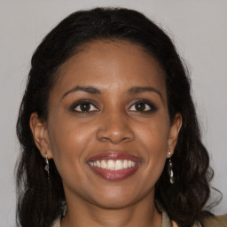 Joyful black young-adult female with long  brown hair and brown eyes