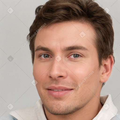 Joyful white young-adult male with short  brown hair and grey eyes