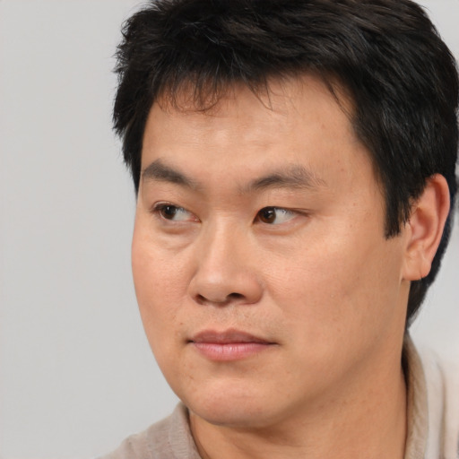 Joyful asian adult male with short  brown hair and brown eyes