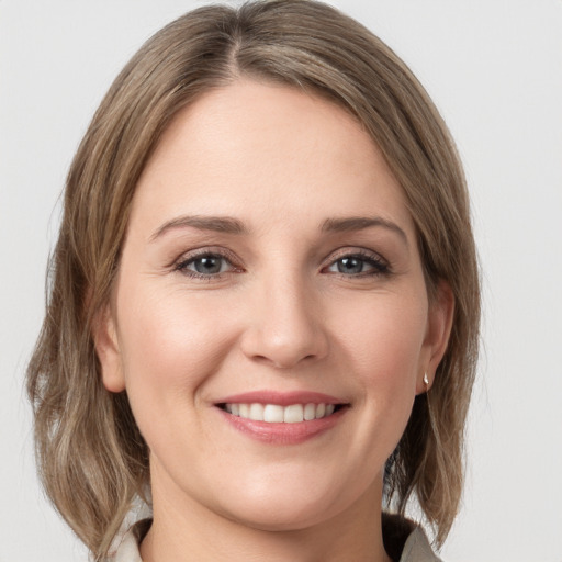 Joyful white young-adult female with medium  brown hair and grey eyes