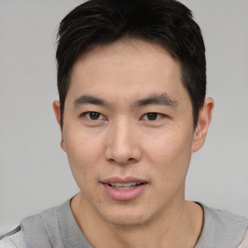 Joyful asian young-adult male with short  brown hair and brown eyes