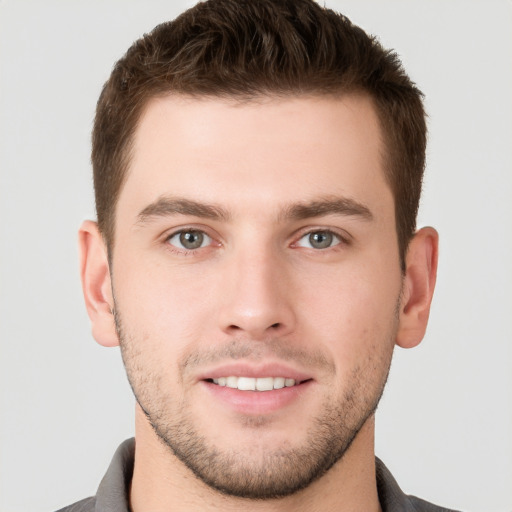 Joyful white young-adult male with short  brown hair and grey eyes