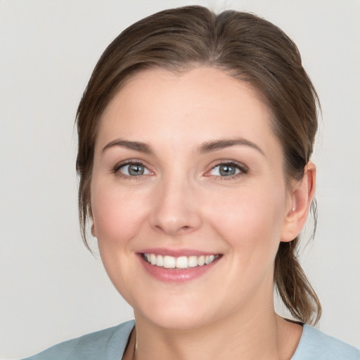 Joyful white young-adult female with medium  brown hair and grey eyes