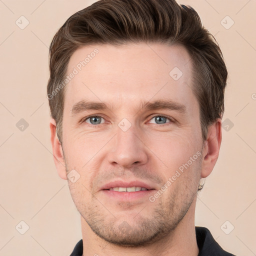 Joyful white young-adult male with short  brown hair and grey eyes