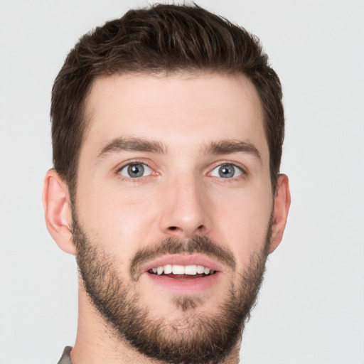 Joyful white young-adult male with short  brown hair and grey eyes