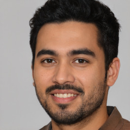 Joyful latino young-adult male with short  black hair and brown eyes