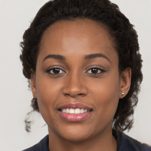 Joyful black young-adult female with long  brown hair and brown eyes