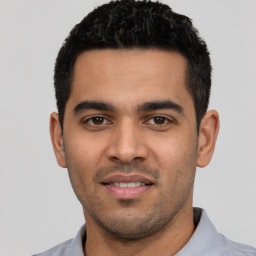 Joyful latino young-adult male with short  black hair and brown eyes