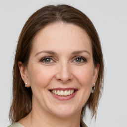 Joyful white adult female with medium  brown hair and green eyes