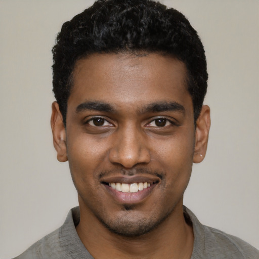 Joyful black young-adult male with short  black hair and brown eyes