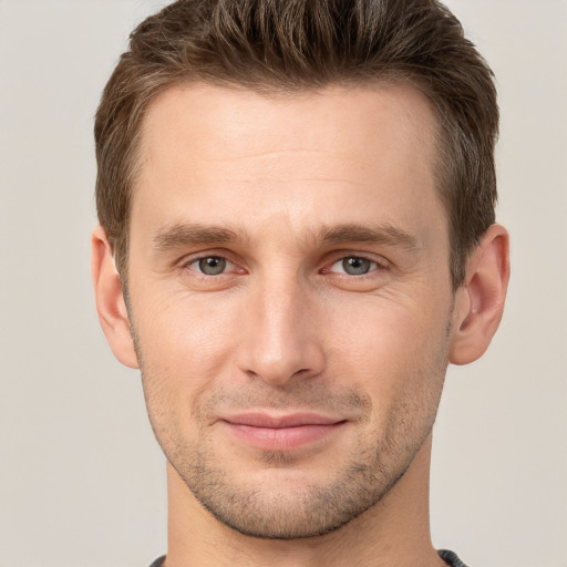 Joyful white young-adult male with short  brown hair and grey eyes