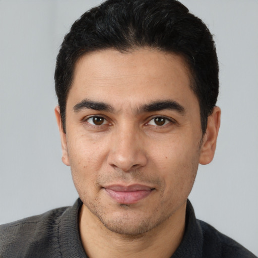 Joyful latino young-adult male with short  black hair and brown eyes