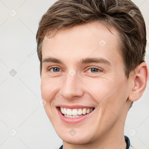 Joyful white young-adult male with short  brown hair and grey eyes