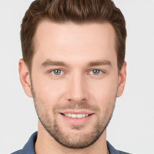 Joyful white young-adult male with short  brown hair and grey eyes