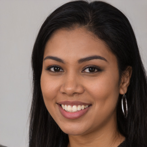 Joyful latino young-adult female with long  brown hair and brown eyes