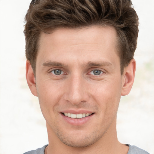 Joyful white young-adult male with short  brown hair and grey eyes