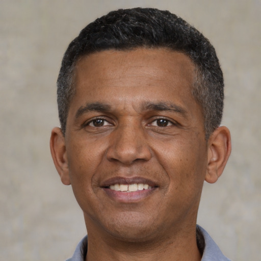 Joyful black adult male with short  black hair and brown eyes