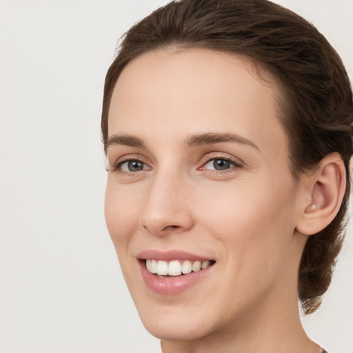 Joyful white young-adult female with medium  brown hair and grey eyes