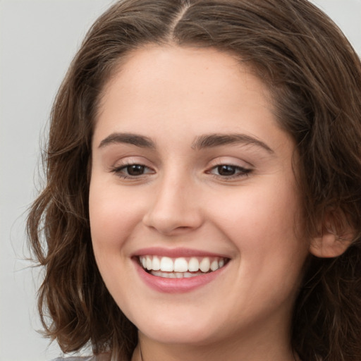 Joyful white young-adult female with long  brown hair and green eyes