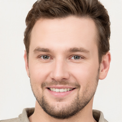 Joyful white young-adult male with short  brown hair and grey eyes