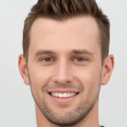 Joyful white young-adult male with short  brown hair and grey eyes