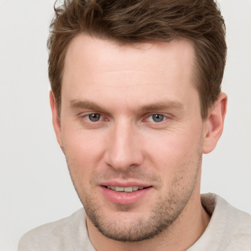 Joyful white young-adult male with short  brown hair and grey eyes