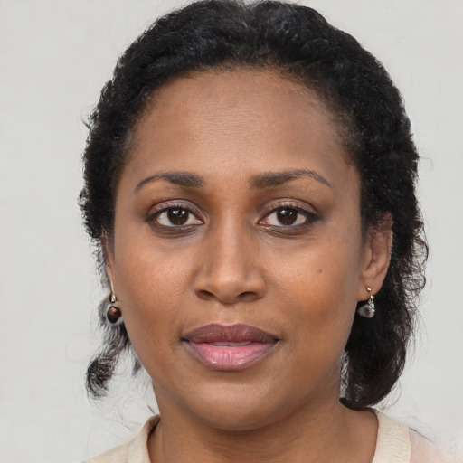 Joyful black adult female with long  brown hair and brown eyes