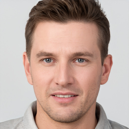 Joyful white young-adult male with short  brown hair and grey eyes