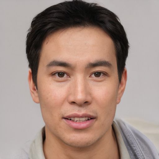 Joyful asian young-adult male with short  brown hair and brown eyes