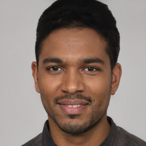 Joyful black young-adult male with short  black hair and brown eyes